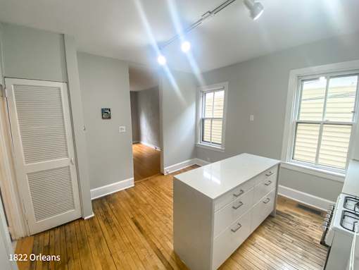 A room with a white desk and wooden floors.