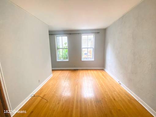 A room with wooden floors and two windows.