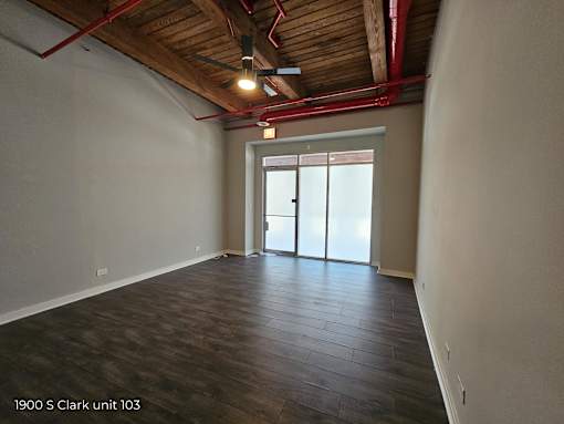 an empty living room with wood floors and a door to the kitchen