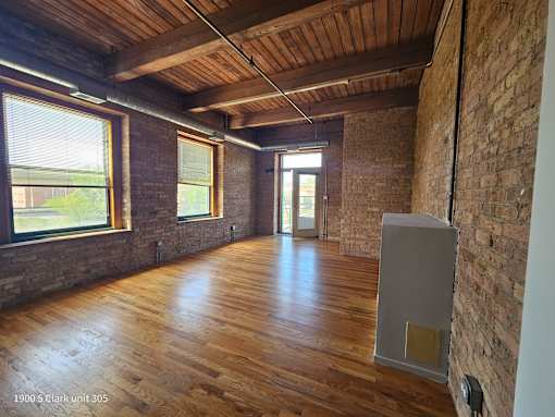an empty room with wood floors and brick walls