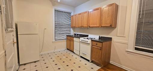 A kitchen with white appliances and wooden cabinets.