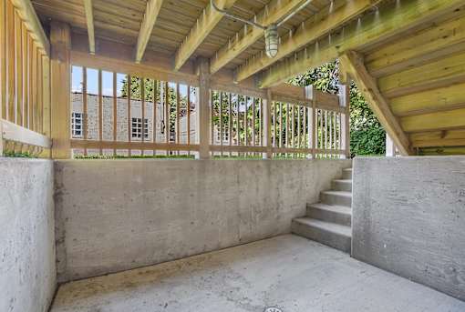 A wooden balcony with concrete stairs and walls.
