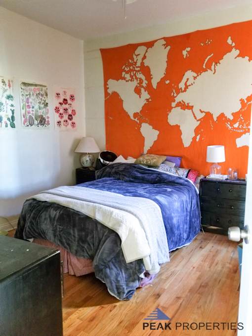 a bedroom with an orange wall and a bed with a blue comforter