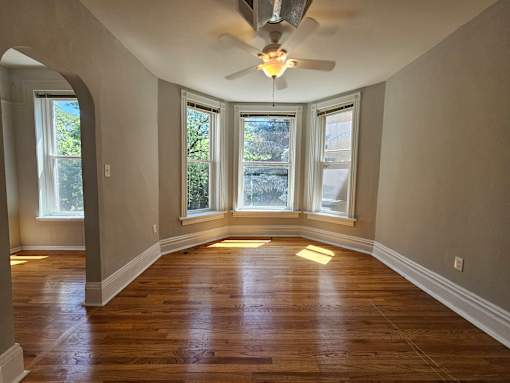 A room with a ceiling fan and wooden floors.