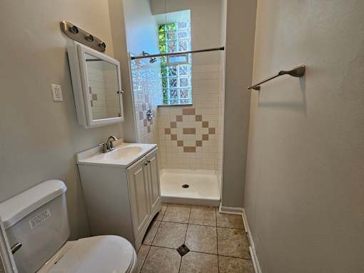 A bathroom with a toilet, sink, and shower.