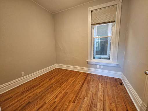A room with wooden floors and a window with blinds.