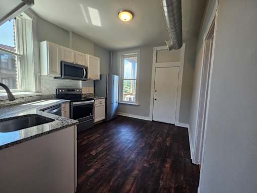 A kitchen with dark wood floors and white cabinets.