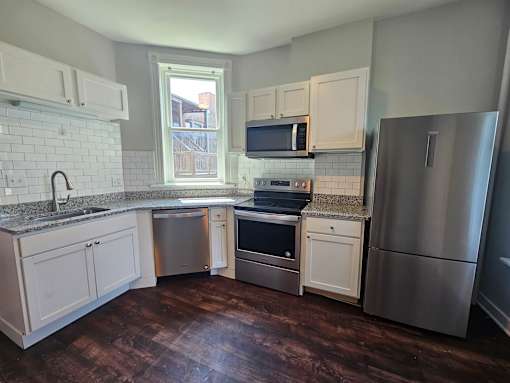 A kitchen with white cabinets and a stainless steel refrigerator.