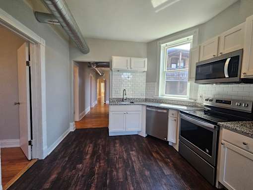 A kitchen with white cabinets and a black stove top oven.