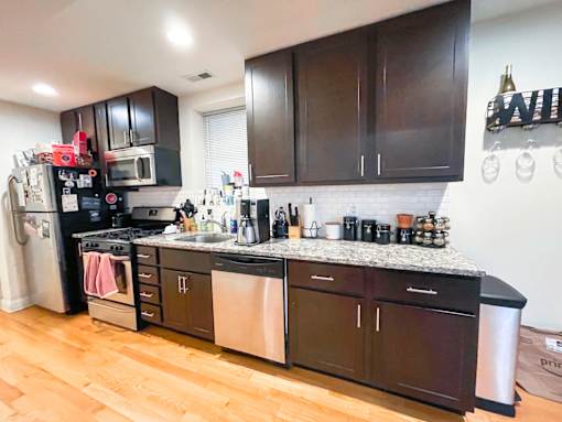 A kitchen with dark brown cabinets and a white tile backsplash.