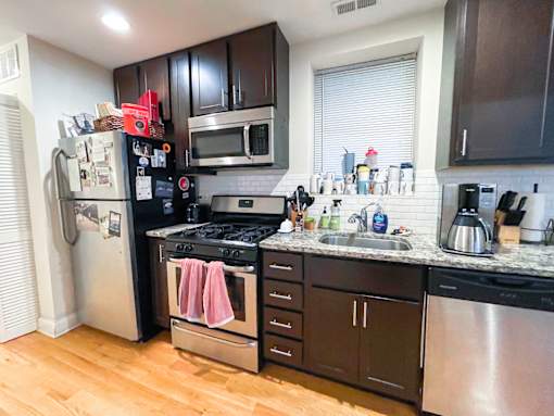 A kitchen with black cabinets and a stainless steel dishwasher.