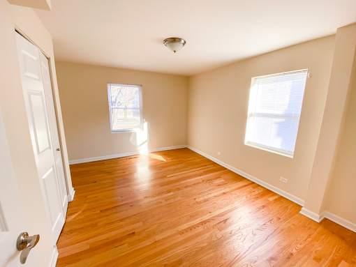 an empty living room with a hard wood floor and two windows