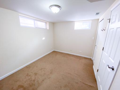 an empty room with carpet and two windows