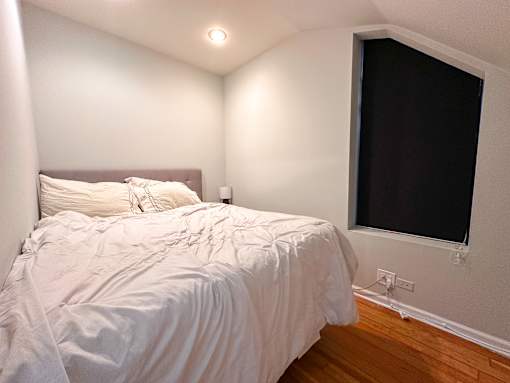 A bed with white bedding sits in a room with a window.