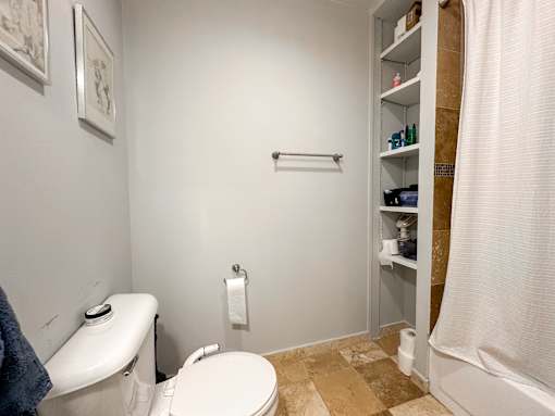 A white toilet sits next to a white toilet paper roll in a bathroom.