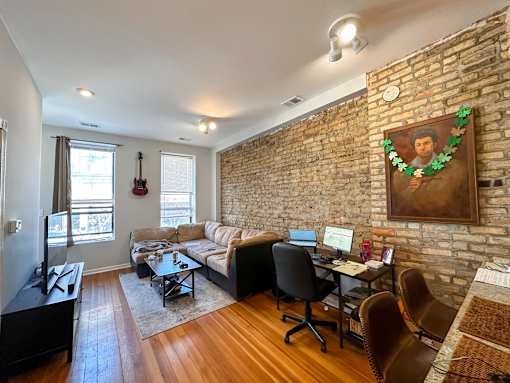A living room with a brick wall and a guitar hanging on it.