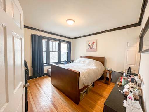 A bedroom with a bed, nightstand, and window.