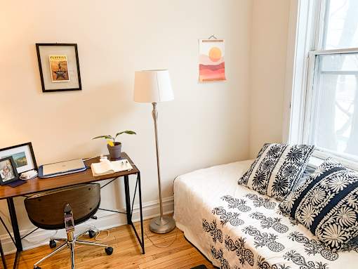 A bedroom with a bed, desk, chair, and pictures on the wall.