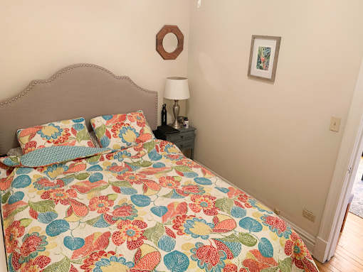 A bed with a floral patterned comforter and a lamp on a side table.