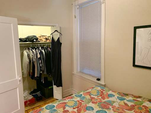 A bedroom with a bed, a wardrobe, and a painting on the wall.