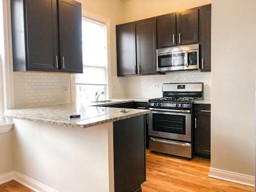 A kitchen with black cabinets and a granite countertop.