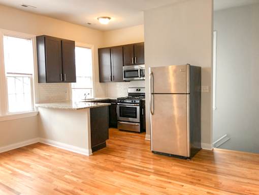 A kitchen with a refrigerator, oven, and microwave.