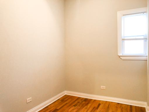 A room with a window and wooden flooring.