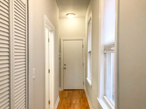 A hallway with a wooden floor and white walls.