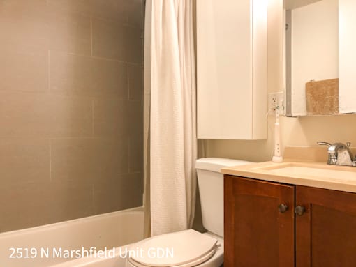A bathroom with a toilet, sink, and mirror.
