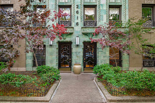 A green building with a black gate and a large door.