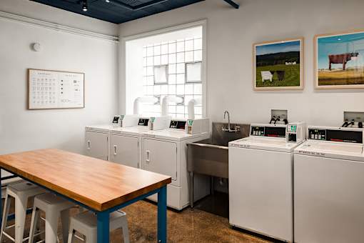 A kitchen with a table, chairs, and a calendar on the wall.