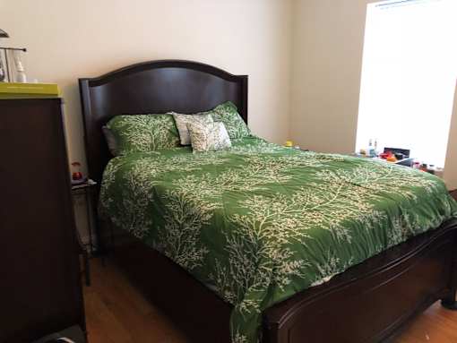 a bedroom with a bed with a green comforter and pillows