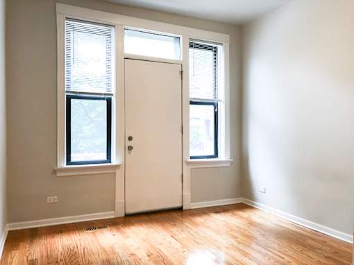 an empty room with a door and two windows