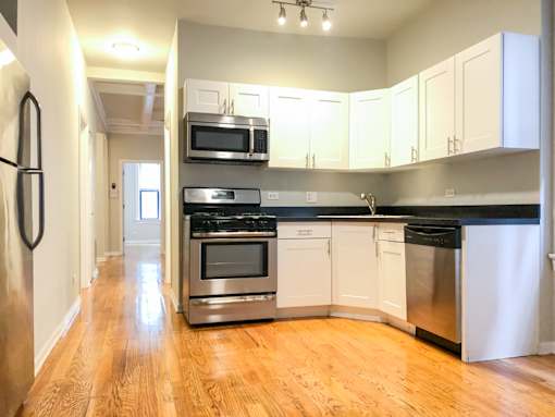 an empty kitchen with stainless steel appliances and white cabinets