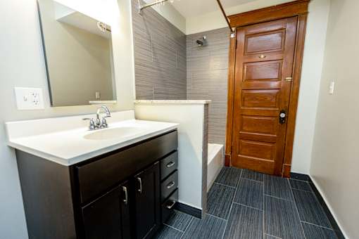 A bathroom with a sink, mirror, and wooden door.