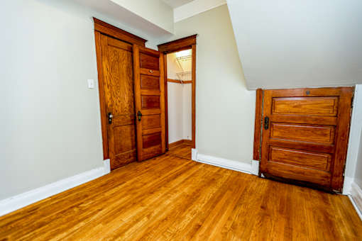 A room with wooden floors and three wooden doors.