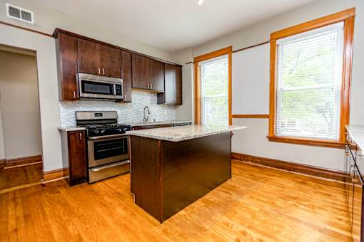 A kitchen with wooden cabinets and a black island.