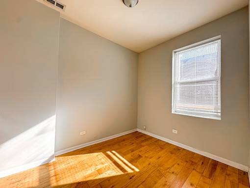 A room with a window and wooden flooring.