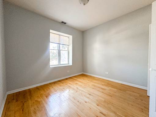 A room with wooden flooring and a window letting in light.