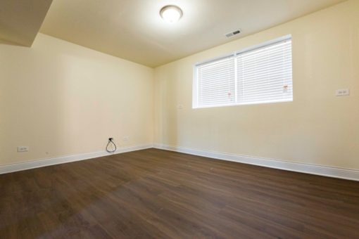 A room with wooden flooring and a window with blinds.