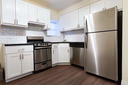 A kitchen with white cabinets and a stainless steel refrigerator.