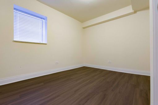 A room with wooden flooring and a window with blinds.