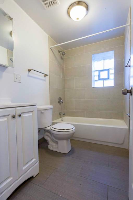 A white toilet sits next to a white bathtub in a bathroom.