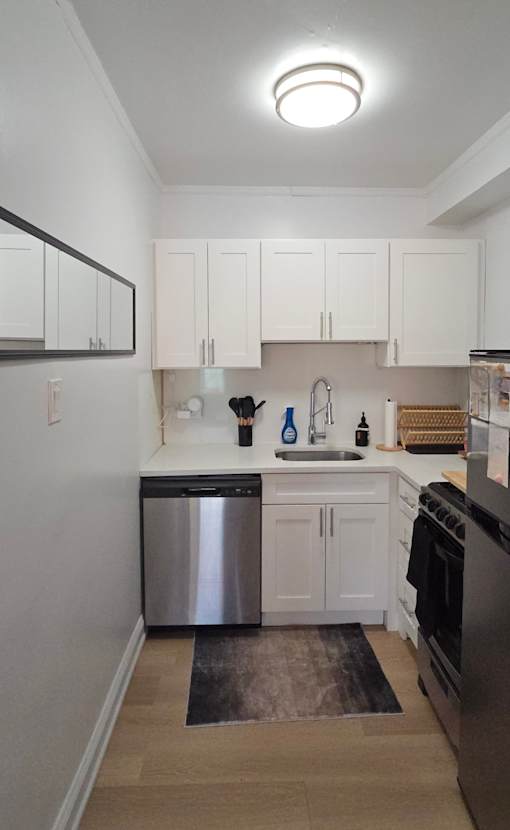 A kitchen with white cabinets and a stainless steel dishwasher.