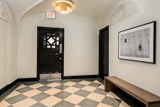 A black door with a window in the middle is flanked by two white walls.
