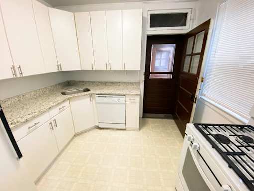 A kitchen with white cabinets and a black fridge.