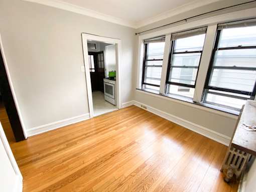 A room with wooden flooring and a window overlooking a cityscape.