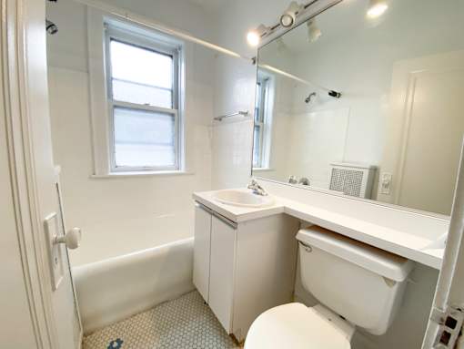 A white bathroom with a toilet, sink, and mirror.