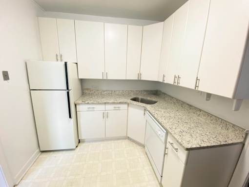 A kitchen with white cabinets and a granite countertop.