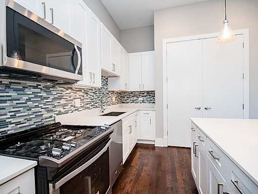 A kitchen with white cabinets and a black stove top oven.